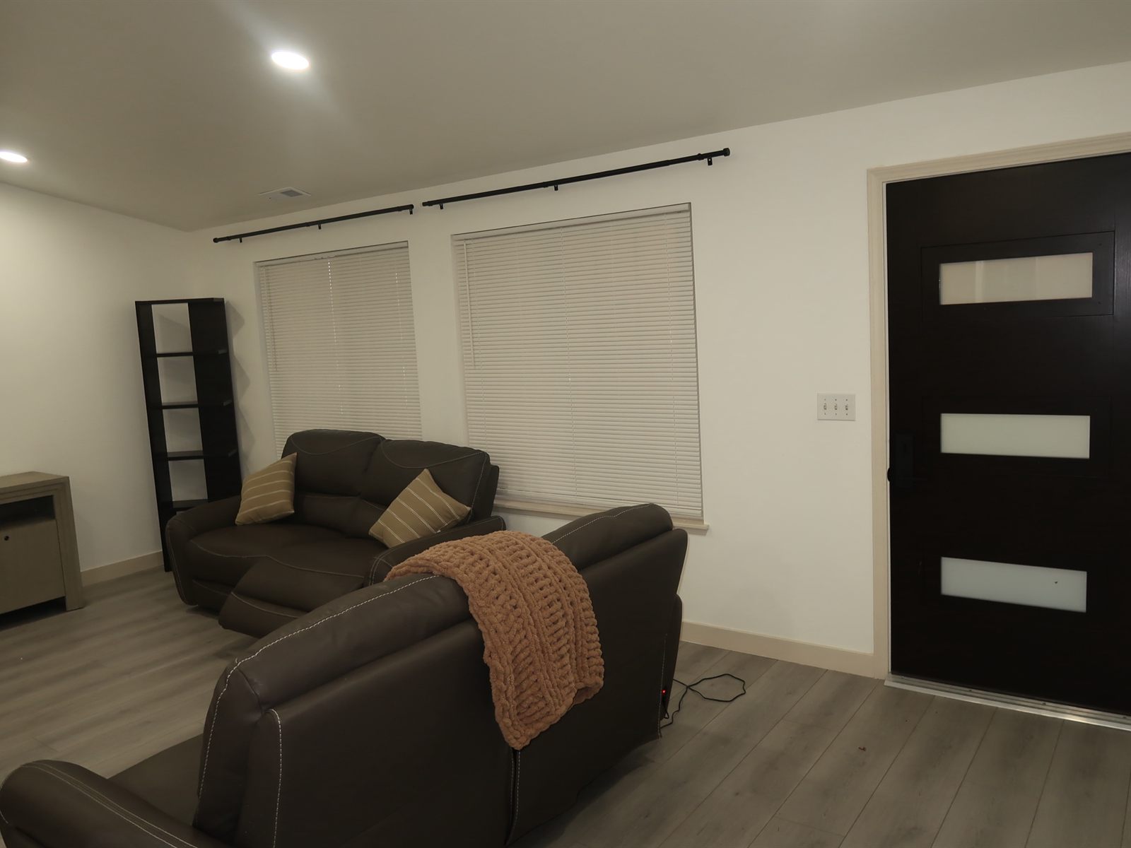 The living room looking toward the front door, with seating and daylight from two windows